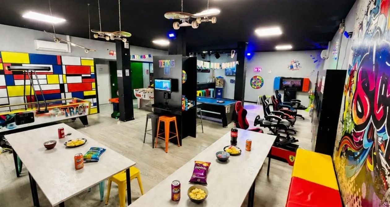 Interior del salón Teens en Fuengirola: mesas para la merienda, consolas, simulador, billar y mural de graffiti
